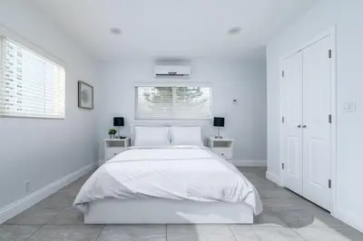 a white bedroom with a white bed and two windows at Bayshore Breeze 10 in Fort Lauderdale