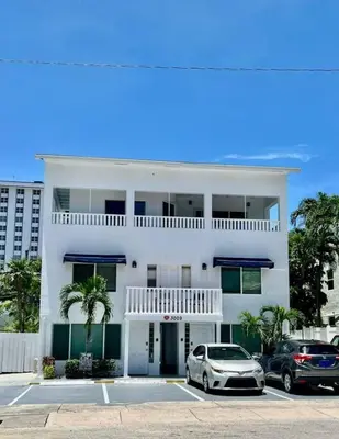 a white house with two cars parked in a parking lot at Ocean Breeze Free Parking Apt 2 in Fort Lauderdale