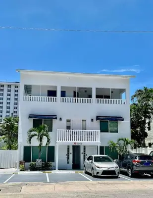 a white house with two cars parked in a parking lot at Ocean Breeze Free Parking Apt 5 in Fort Lauderdale