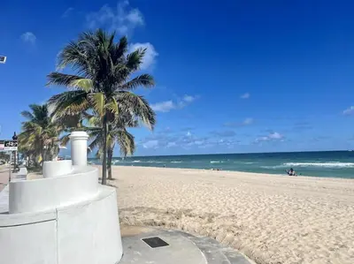 a sandy beach with palm trees and the ocean at Ocean Breeze Paradise Apt 5A in Fort Lauderdale