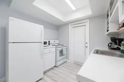 a white kitchen with a refrigerator and a sink at Short Walk to Wilton Drive Apt1 in Fort Lauderdale