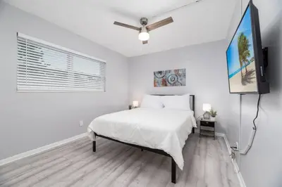 a white bedroom with a bed and a flat screen tv at Short Walk to Wilton Drive Apt4 in Fort Lauderdale