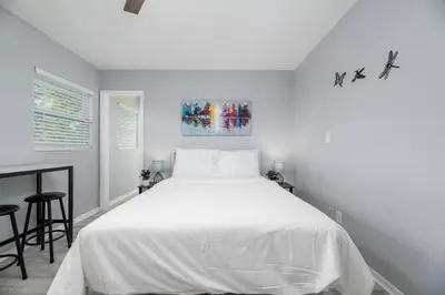 a white bedroom with a large bed and a table at Short Walk to Wilton Drive Apt5 in Fort Lauderdale