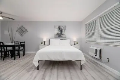 a white bedroom with a large bed and a table at Just Off Wilton Drive Apt 3 in Fort Lauderdale