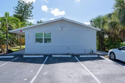 a white house with a car parked in a parking lot at Just Off Wilton Drive Apt 4 in Fort Lauderdale