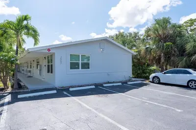a white house with a car parked in a parking lot at Just Off Wilton Drive Apt 7 in Fort Lauderdale