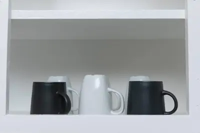 four black and white mugs on a shelf at Just Off Wilton Drive Apt 8 in Fort Lauderdale