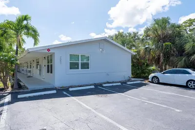 a white house with a car parked in a parking lot at Just Off Wilton Drive Apt 8 in Fort Lauderdale