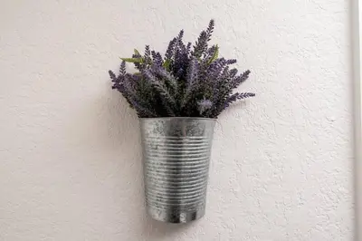 a metal vase with purple flowers in it on a wall at Comfy Condos at Middle River Apt 3 in Fort Lauderdale
