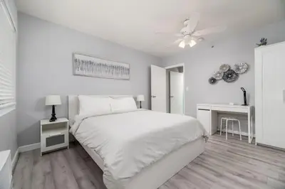 a white bedroom with a bed and a ceiling fan at The Dolphin Studio at Lake Ridge in Fort Lauderdale