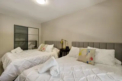 a bedroom with two beds with white sheets and a mirror at Designer Home w Pool & Firepit - 7 min to Brickell in Miami
