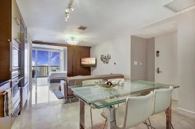 a dining room with a glass table and a couch at Lux 2BR - Water View - Pool - Spa - FREE Parking in Miami