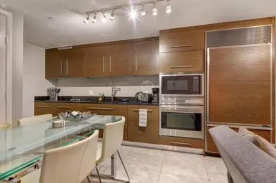 a kitchen with wooden cabinets and a table with chairs at Lux 2BR - Water View - Pool - Spa - FREE Parking in Miami