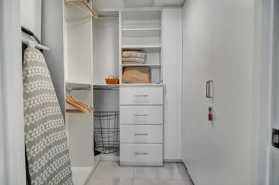 a closet with white cabinets and a surfboard in it at Lux 2BR - Water View - Pool - Spa - FREE Parking in Miami