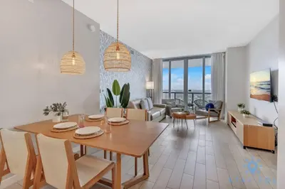 a dining room and living room with a table and chairs at Upper Apartment - Pool - Gym - Near Beach in Hallandale Beach