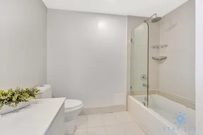 a white bathroom with a tub and a toilet at Upper Apartment - Pool - Gym - Near Beach in Hallandale Beach