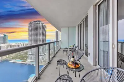 a balcony with chairs and tables and a view of the city at Upper Apartment - Pool - Gym - Near Beach in Hallandale Beach