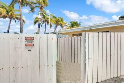 a white fence in front of a house with palm trees at Chic Studio Apartment in Hollywood Beach in Hollywood
