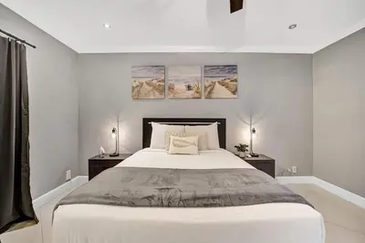 a white bedroom with a large bed with two night stands at Beach Isles Modern 1BR Waterfront Apartment with Patio in Fort Lauderdale