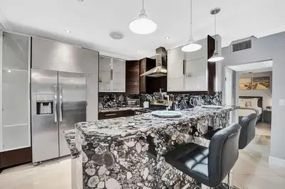 a kitchen with a large marble counter with chairs at Beach Isles Modern 1BR Waterfront Apartment with Patio in Fort Lauderdale