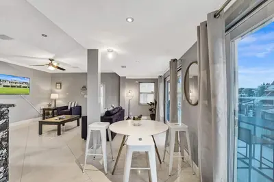 a living room with a white table and stools at Beach Isles Modern 1BR Waterfront Apartment with Patio in Fort Lauderdale