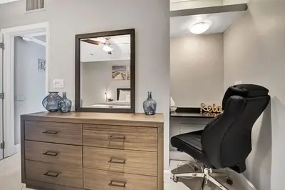 a black chair sitting next to a dresser with a mirror at Beach Isles Modern 1BR Waterfront Apartment with Patio in Fort Lauderdale