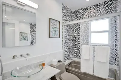 a white bathroom with a tub and a sink at Beach Isles Modern 1BR Apartment in Fort Lauderdale in Fort Lauderdale
