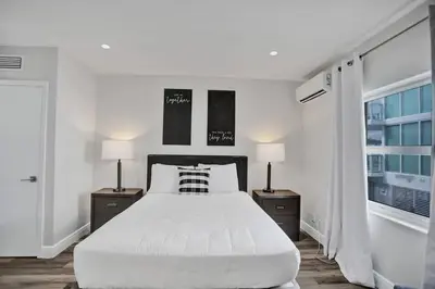 a white bedroom with a large bed and two lamps at Beach Isles Modern Studio Apartment in Fort Lauderdale in Fort Lauderdale