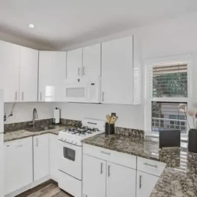 a kitchen with white cabinets and marble counter tops at Beach Isles Modern Studio Apartment in Fort Lauderdale in Fort Lauderdale
