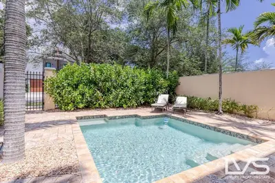 a swimming pool with two chairs in a yard at LVS Villa Alba- Walk2LasOlas, HeatedPool, RoofTopTerrace in Fort Lauderdale