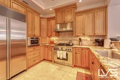 a kitchen with wooden cabinets and a stainless steel refrigerator at LVS Villa Alba- Walk2LasOlas, HeatedPool, RoofTopTerrace in Fort Lauderdale