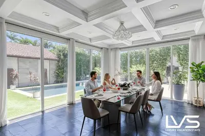 a group of people sitting around a table in a dining room at Poinciana-LuxeHome Wlk2Beach HeatedPool HotTub in Fort Lauderdale