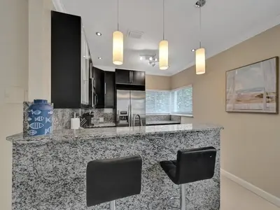 a kitchen with a counter with two black chairs at Beach Isles Modern 1BR in Fort Lauderdale with Patio in Fort Lauderdale