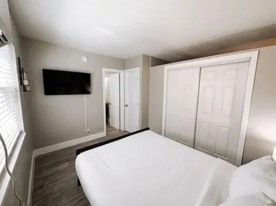 a bedroom with a white bed and a flat screen tv at Rustic Retreats Cozy 1BR For 4 Guests Minutes From Las Olas in Fort Lauderdale