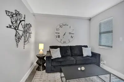 a living room with a couch and a clock on the wall at Rustic Retreats Modern 1BR For 4 Guests Minutes From Las Olas in Fort Lauderdale