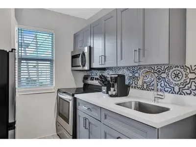 a white kitchen with a sink and a stove at Rustic Retreats Cozy 1BR For 4 Guests In The Heart Of Fort Lauderdale in Fort Lauderdale