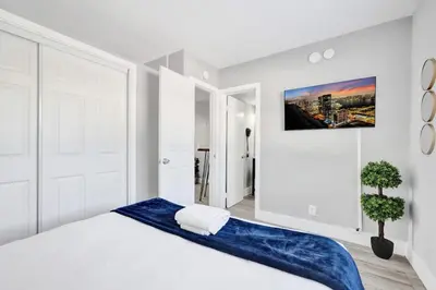 a white bedroom with a large bed with blue sheets at Rustic Retreats Cozy 1BR For 4 Guests Minutes From Las Olas in Fort Lauderdale