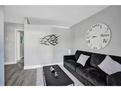 a living room with a couch and a clock on the wall at Rustic Retreats Cozy 1BR For 4 Guests Minutes From Las Olas in Fort Lauderdale