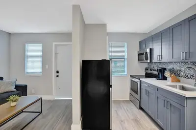 a kitchen with a black refrigerator and a living room at Rustic Retreats Cozy 1BR for 2 guests minutes from Las Olas in Fort Lauderdale
