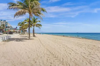 a sandy beach with palm trees and the ocean at Rustic Retreats Cozy 1BR for 2 guests minutes from Las Olas in Fort Lauderdale