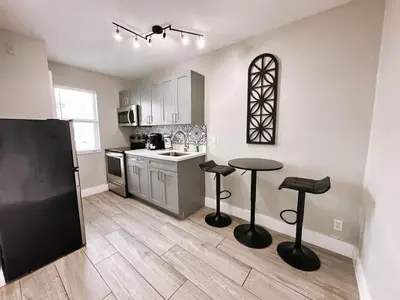 a kitchen with a black refrigerator and two stools at Rustic Retreats Cozy 1BR For 4 Guests Minutes From Las Olas in Fort Lauderdale