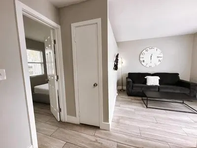 a living room with a couch and a clock on the wall at Rustic Retreats Cozy 1BR For 4 Guests Minutes From Las Olas in Fort Lauderdale