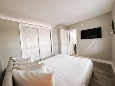 a bedroom with a white bed and a flat screen tv at Rustic Retreats Cozy 1BR For 4 Guests Minutes From Las Olas in Fort Lauderdale