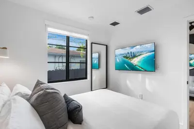 a white room with a couch and a tv on a wall at Lux Retreat By Renzzi in Miami