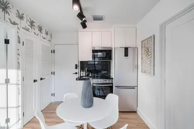 a white kitchen with a white table and chairs at Lux Retreat By Renzzi in Miami