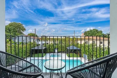 a balcony with chairs and a pool with a fence at Lux Retreat By Renzzi in Miami