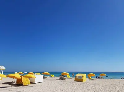 a beach with yellow chairs and umbrellas and the ocean at Miami Beach Getaway 100 yards from Beach in Miami Beach