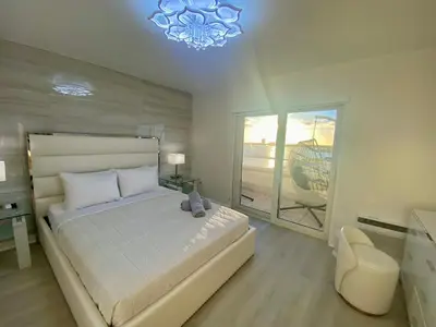 a bedroom with a bed and a chair and a window at Panoramic luxurious waterfront one bedroom apartment with Miami skyline view Free parking 5min drive to Miami Beach in Miami Beach