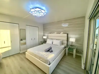 a bedroom with a large white bed and a chandelier at Panoramic luxurious waterfront one bedroom apartment with Miami skyline view Free parking 5min drive to Miami Beach in Miami Beach