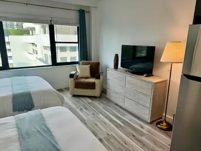 a bedroom with a bed and a tv and a chair at Directly on the Beach with Pool & Parking in Miami Beach